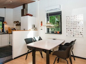 Una cocina moderna con armarios blancos, encimera de madera y una lámpara colgante.