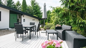 A patio with a table and chairs, a sofa, and a covered umbrella. - 4 Star Holiday Home in Ebeltoft (Ebeltoft)