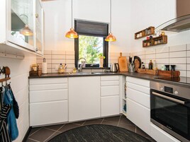 Una cocina moderna con armarios blancos, horno Bosch, ventana con vistas y luces colgantes.