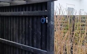 En träkonstruktion med en metalldörr, ett blått lås och ett metallhandtag.