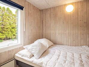 A bedroom with a bed, pillows, a window, and a wall-mounted light fixture. - 8 Person Holiday Home in Otterup (Otterup)