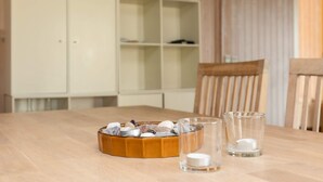 A wooden table with a bowl of snacks, two clear glasses with candles, and a white cabinet in the background. - 8 Person Holiday Home in Otterup (Otterup)