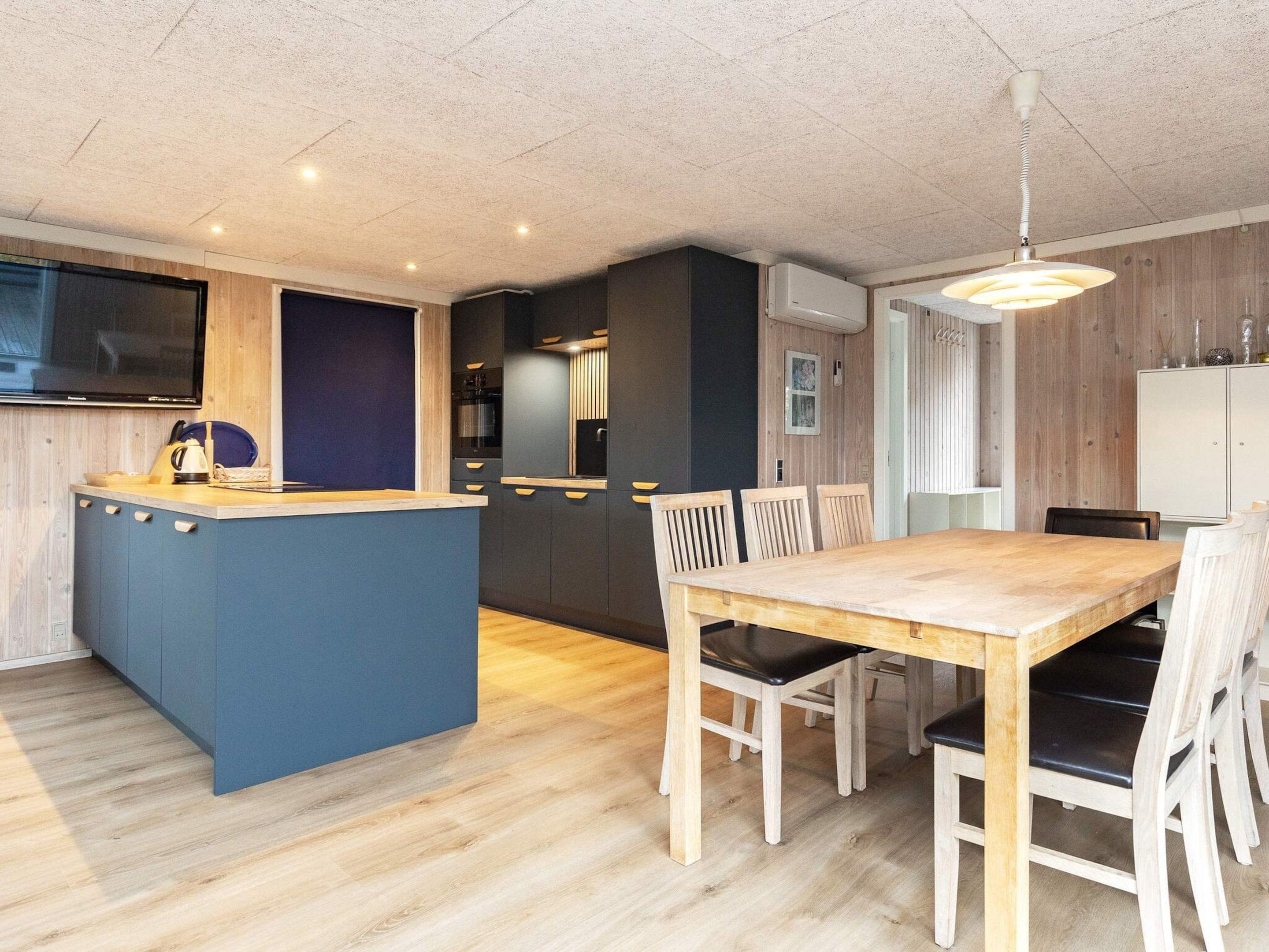 Et moderne køkken med en central ø, et træspisebord og stole.
