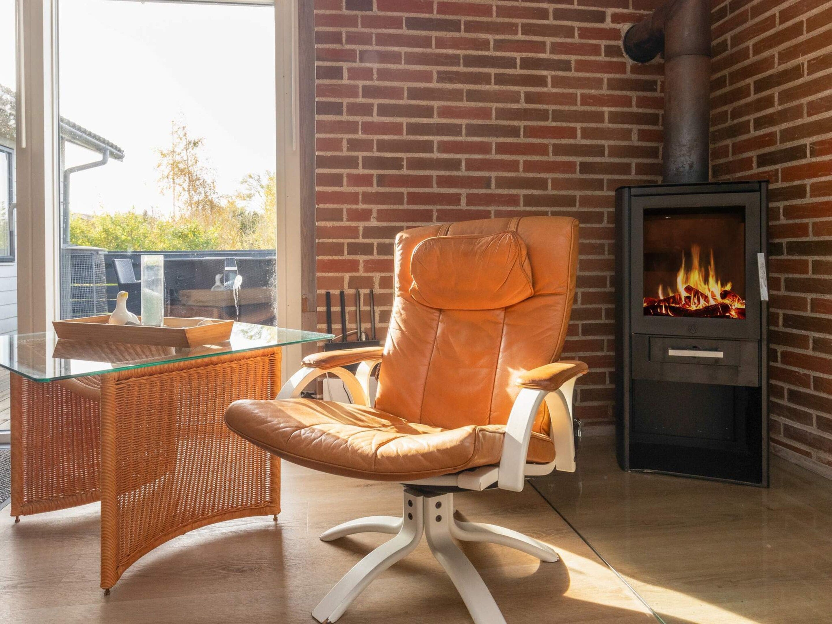 Un espace de détente moderne comprenant un fauteuil en cuir, une table en verre, un fauteuil en osier et un poêle à bois.