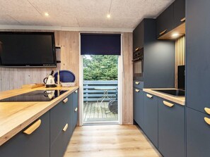 A modern kitchen with a wooden countertop, dark cabinets, and a large window.