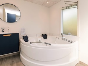 A modern bathroom with a freestanding bathtub, a round mirror, and a dark-colored vanity. - 8 Person Holiday Home in Otterup (Otterup)