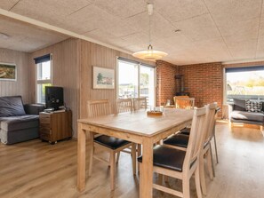 A modern living room with a wooden dining table, chairs, a sofa, and a television. - 8 Person Holiday Home in Otterup (Otterup)