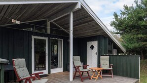A wooden deck with outdoor seating, a covered area, and a door with glass panels. - 6 Person Holiday Home in Blokhus (Blokhus)