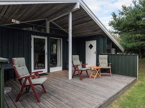 A wooden deck with outdoor seating, a covered area, and a door with glass panels. - 6 Person Holiday Home in Blokhus (Blokhus)