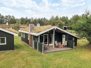 A small cabin with a sloped roof, a chimney, and a deck with outdoor furniture.