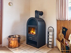 A room with a wood-burning stove, a metal pot, and a wicker basket with magazines. - 6 Person Holiday Home in Blokhus (Blokhus)