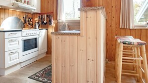 A kitchen with wooden walls, a white stove, and a window with curtains. - 6 Person Holiday Home in Blokhus (Blokhus)