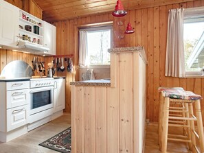 A kitchen with wooden walls, a white stove, and a window with curtains. - 6 Person Holiday Home in Blokhus (Blokhus)