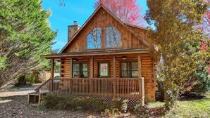A log cabin with a porch, large windows, and a chimney. - Creekside Fish Cabin (Hiawassee)