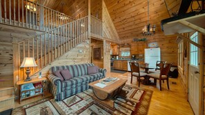 Cozy cabin interior with a central living area, staircase, and kitchen.