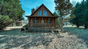 Set amidst a serene natural landscape, this cabin features a gabled roof and a large window.