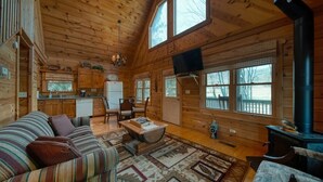 A cozy cabin interior with a wooden interior, a dining area, a kitchen, and a fireplace. - Creekside Fish Cabin (Hiawassee)