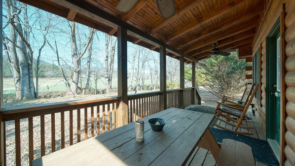 Enjoy a peaceful retreat with a covered porch featuring a table and bench.