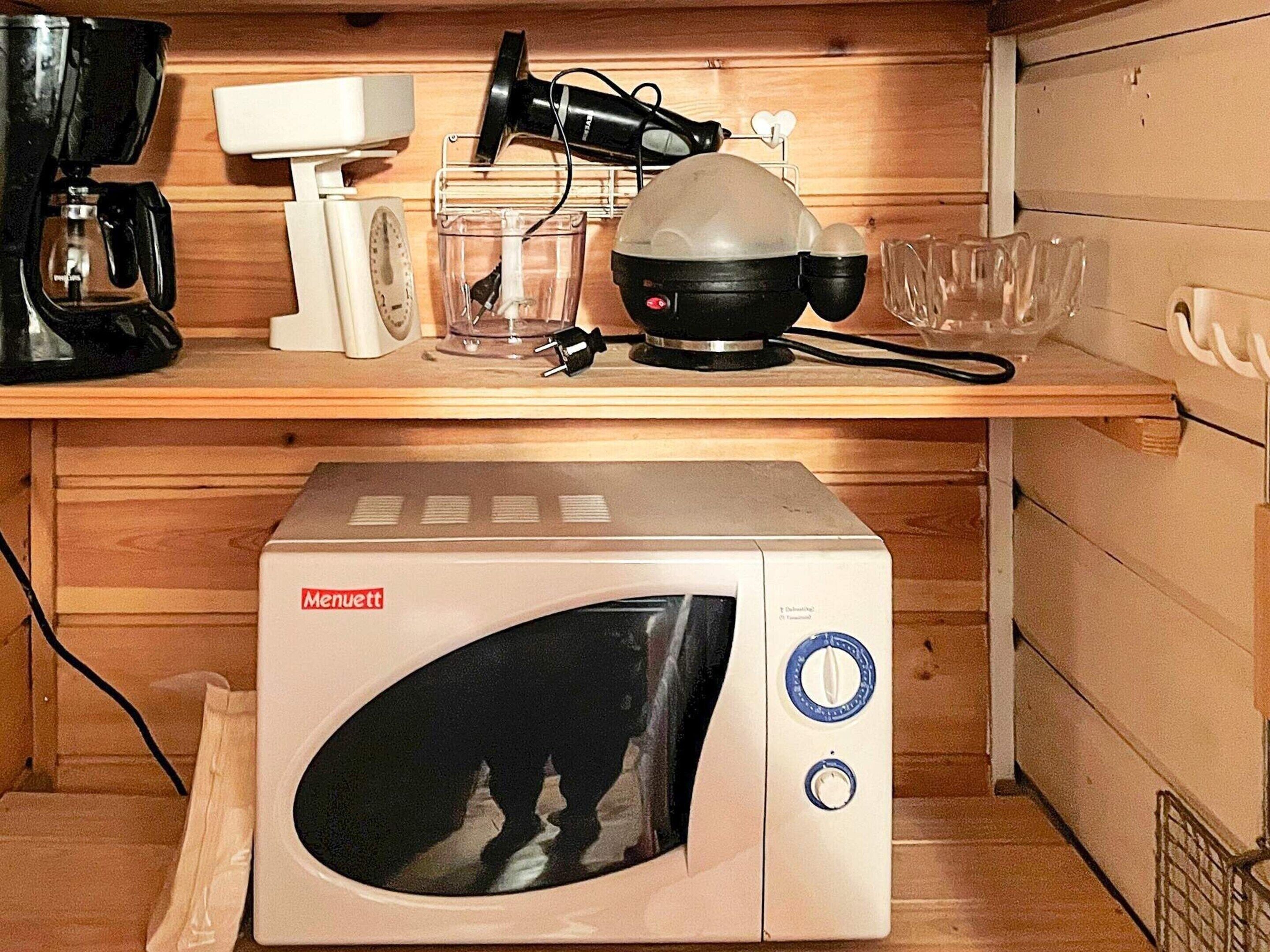 Una kitchenette equipada con microondas, cafetera, secador de pelo y un refrigerador pequeño.