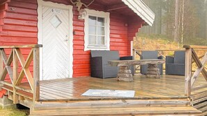 A red cabin with a wooden deck, a door, a window, and two wicker chairs. - 5 Person Holiday Home in Sexdrega-by Traum (Sexdrega)