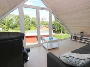 A spacious room with a sloped ceiling, a black leather sofa, a white coffee table, and a bookshelf. - 10 Person Holiday Home in Hadsund (Hadsund)