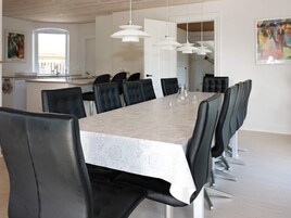 Un comedor moderno con una mesa larga, sillas negras e iluminación colgante.