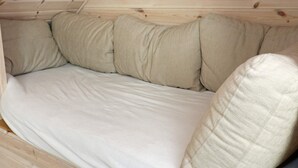 Una habitación con techo de madera inclinado y una cama con ropa de cama color beige.