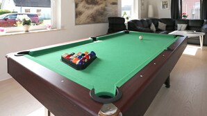 Una mesa de billar con bolas en una sala con vistas al exterior.