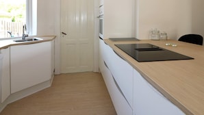Una cocina con encimera de madera, horno empotrado y puerta blanca.