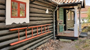A log cabin with a red-framed window, a wooden porch, and a green door. - 5 Person Holiday Home in Lerum-by Traum (Lerum)