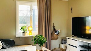 A living room with a sofa, a coffee table with a plant, a TV on a stand, and a window with curtains. - 4 Person Holiday Home in Bottnaryd-by Traum (Bottnaryd)