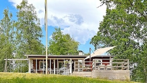 A rustic cabin with a wooden deck, surrounded by lush greenery and trees. - 4 Person Holiday Home in Bottnaryd-by Traum (Bottnaryd)