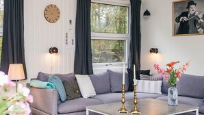 A modern living room with a grey sofa, a coffee table, a clock, and a painting on the wall. - 6 Person Holiday Home in Orsted (Ørsted)