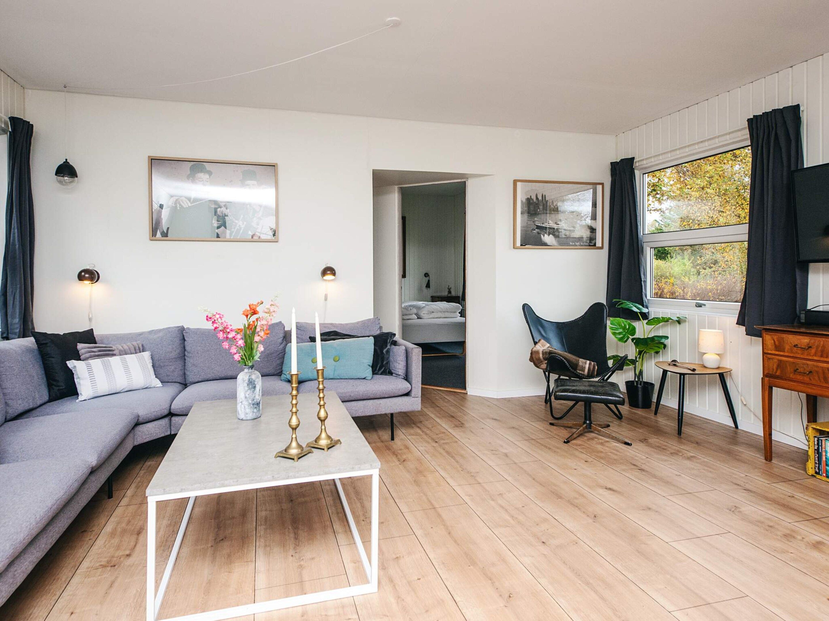 Una sala de estar moderna con un sofá gris, una mesa de centro y una zona de comedor con una silla y una mesa.