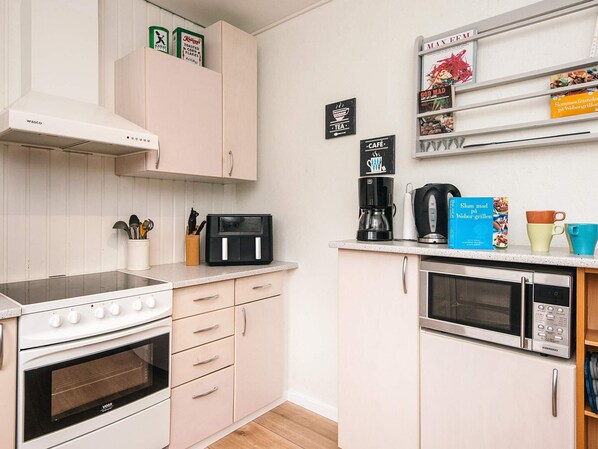 A kitchen with a stove, oven, microwave, and a coffee maker. - 6 Person Holiday Home in Orsted (Ørsted)