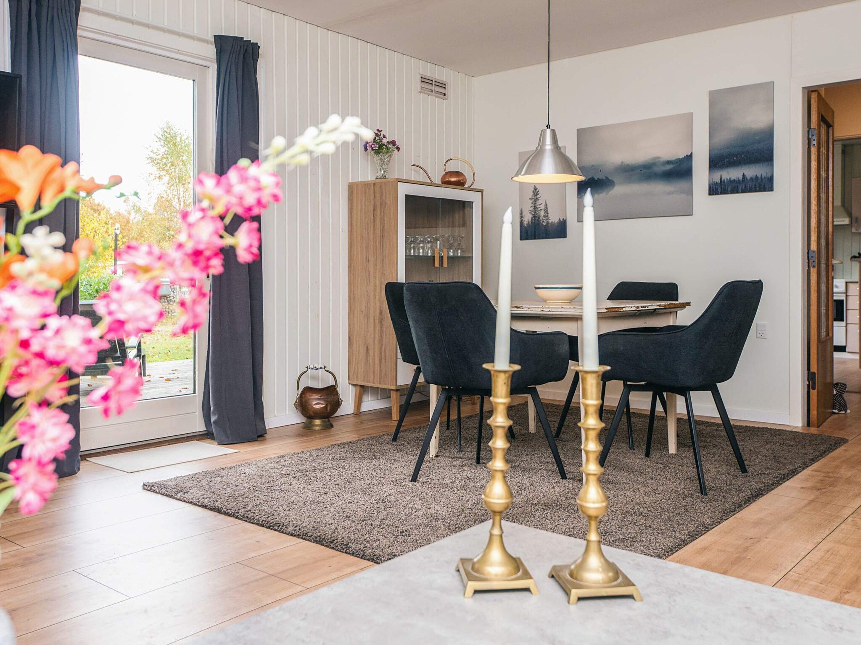 A modern dining area with a wooden cabinet, black chairs, a table, and a hanging pendant light.