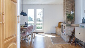 Une cuisine spacieuse avec une cheminée en briques, un plancher en bois et un coin repas comprenant une chaise et une table.