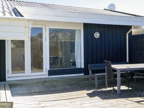 Eine Terrasse mit Tisch und Stühlen, eine Glastür und eine Satellitenschüssel.
