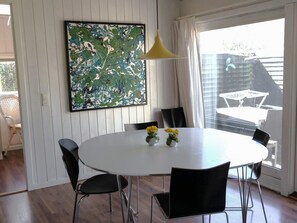 A dining area with a white table, black chairs, a yellow pendant light, and a large abstract painting on the wall. - 8 Person Holiday Home in Saltum (Saltum)