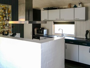 A modern kitchen with white cabinets, a microwave, a sink, and a window. - 8 Person Holiday Home in Saltum (Saltum)