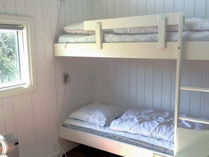 A bunk bed with white bedding and a window on the left side.