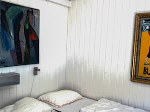 Una habitación con una cama, una pared blanca, un cuadro y una fotografía enmarco.