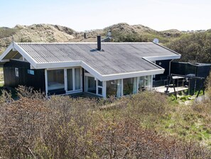 A modern house with a sloped roof, large windows, and a deck. - 8 Person Holiday Home in Saltum (Saltum)