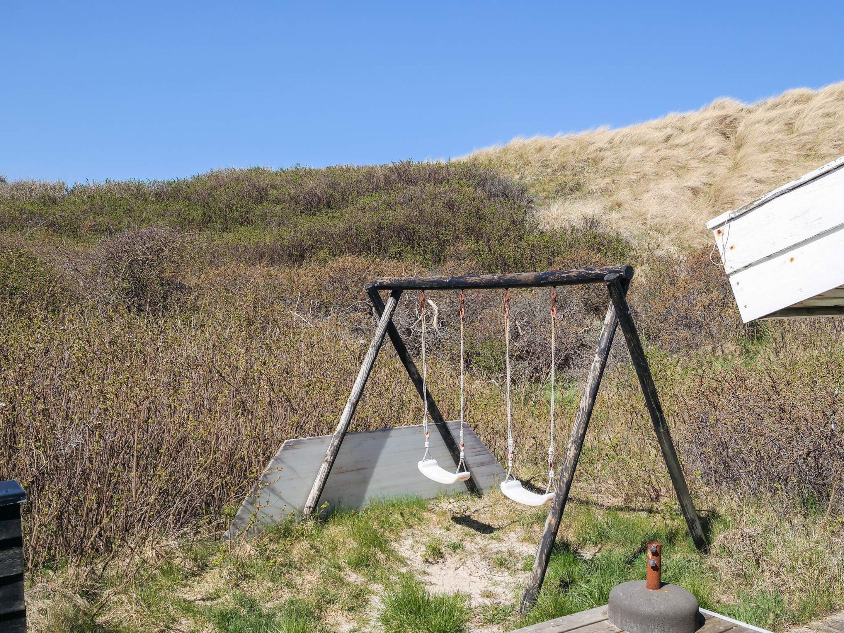 A swing set in a natural setting with a hill in the background.