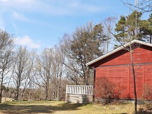 A red barn with a white fence and a wooden deck in front. - 4 Star Holiday Home in Knared (Knared)