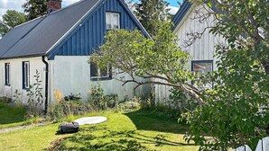 Een woonhuis met twee verdiepingen, een blauw dak en witte muren, omringd door een verzorgd gazon en een witte picket fence.
