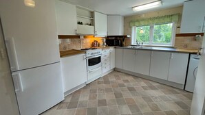 A kitchen with white cabinets, a stove, an oven, a microwave, and a sink. - 4 Person Holiday Home in Everod (Everöd)