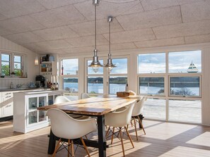 A spacious kitchen with a large island, white cabinetry, and a view of a lake through large windows. - Panoramic Water View - By Traum Ferienwohnungen (Kolding)