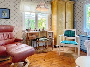 A room with a wooden desk, a red leather chair, a green upholstered chair, and a wardrobe. - 4 Star Holiday Home in Rockneby (Rockneby)