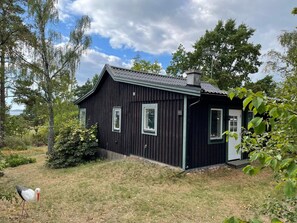 A black wooden house with a number '501' on the side, surrounded by trees and a grassy area. - 4 Star Holiday Home in Rockneby (Rockneby)